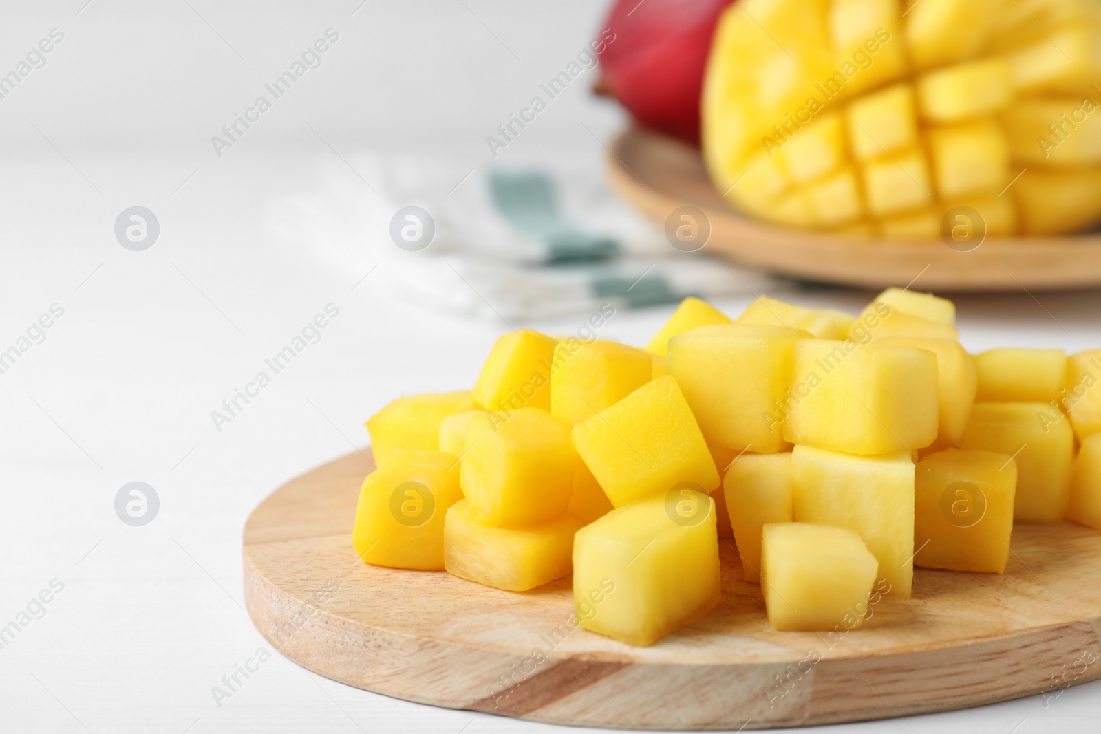 Photo of Cubes of fresh ripe mango on white wooden table