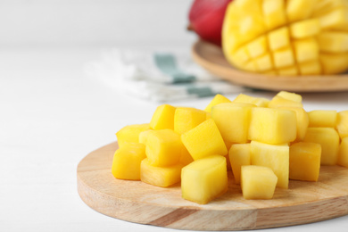 Cubes of fresh ripe mango on white wooden table