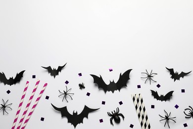 Photo of Flat lay composition with paper bats, spiders and straws on white background, space for text. Halloween celebration