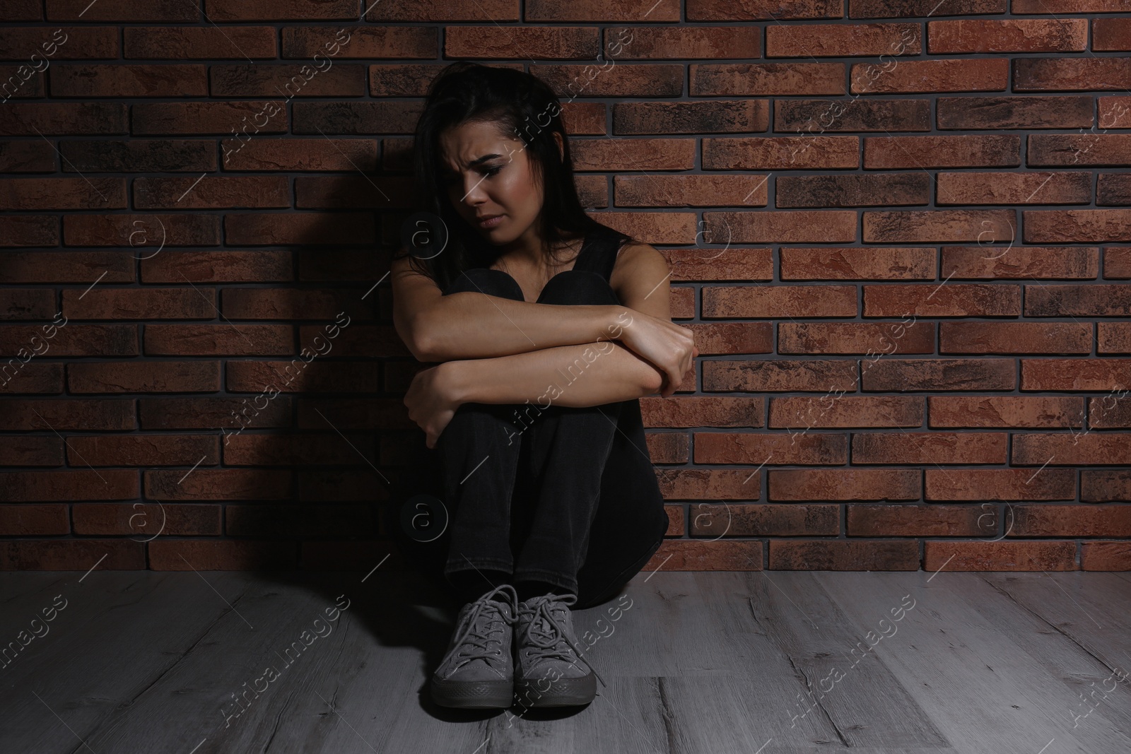 Photo of Abused young woman near brick wall. Domestic violence concept