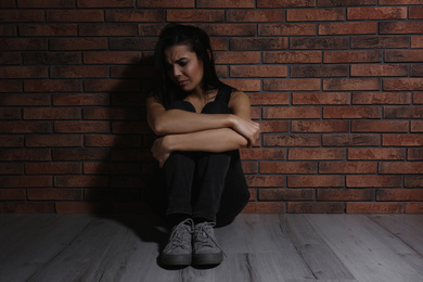 Photo of Abused young woman near brick wall. Domestic violence concept