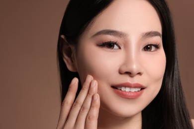 Portrait of beautiful woman on brown background, closeup