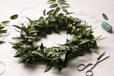 Beautiful handmade mistletoe wreath and florist supplies on white wooden table. Traditional Christmas decor