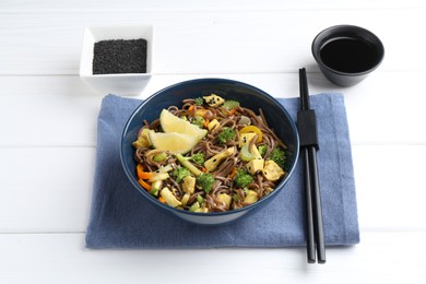 Photo of Stir-fry. Delicious cooked noodles with chicken and vegetables in bowl served on white wooden table, above view