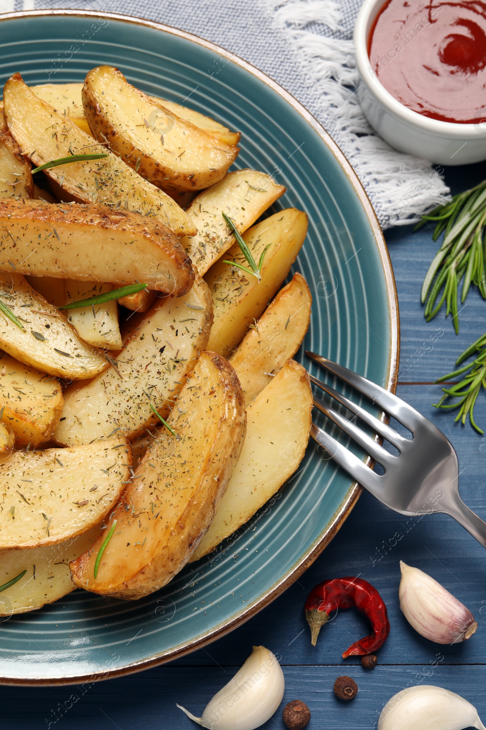 Photo of Delicious baked potatoes with spices on blue wooden table, flat lay