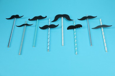 Photo of Fake paper mustaches with party props on light blue background