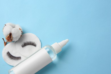 Photo of Bottle of makeup remover, cotton flower, pads and false eyelashes on light blue background, flat lay. Space for text