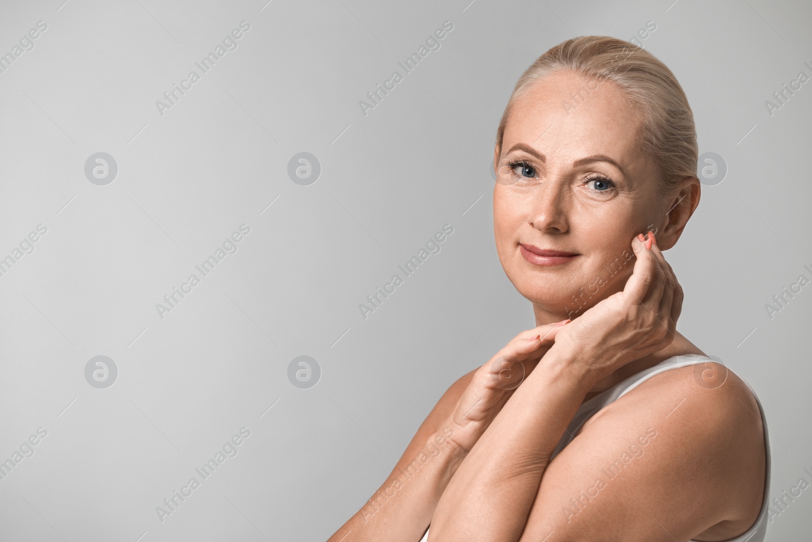 Photo of Portrait of beautiful mature woman with perfect skin on grey background. Space for text