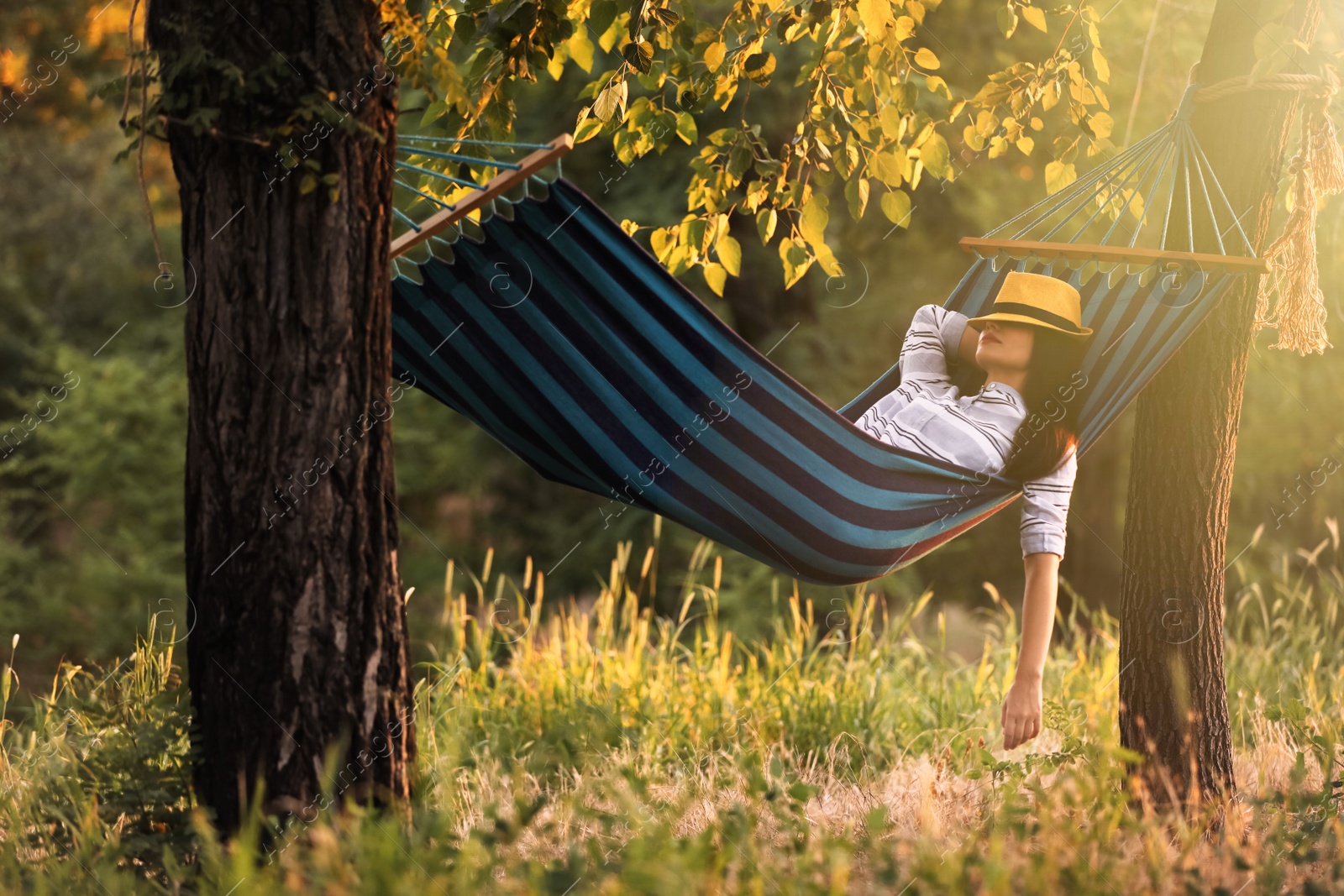 Photo of Young woman resting in comfortable hammock at green garden