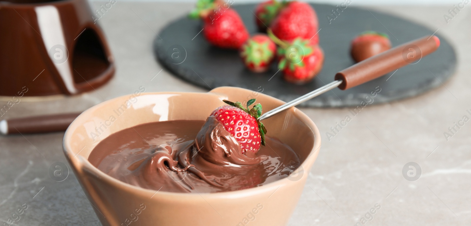 Image of Tasty strawberry dipped into chocolate fondue on table, closeup. Banner design