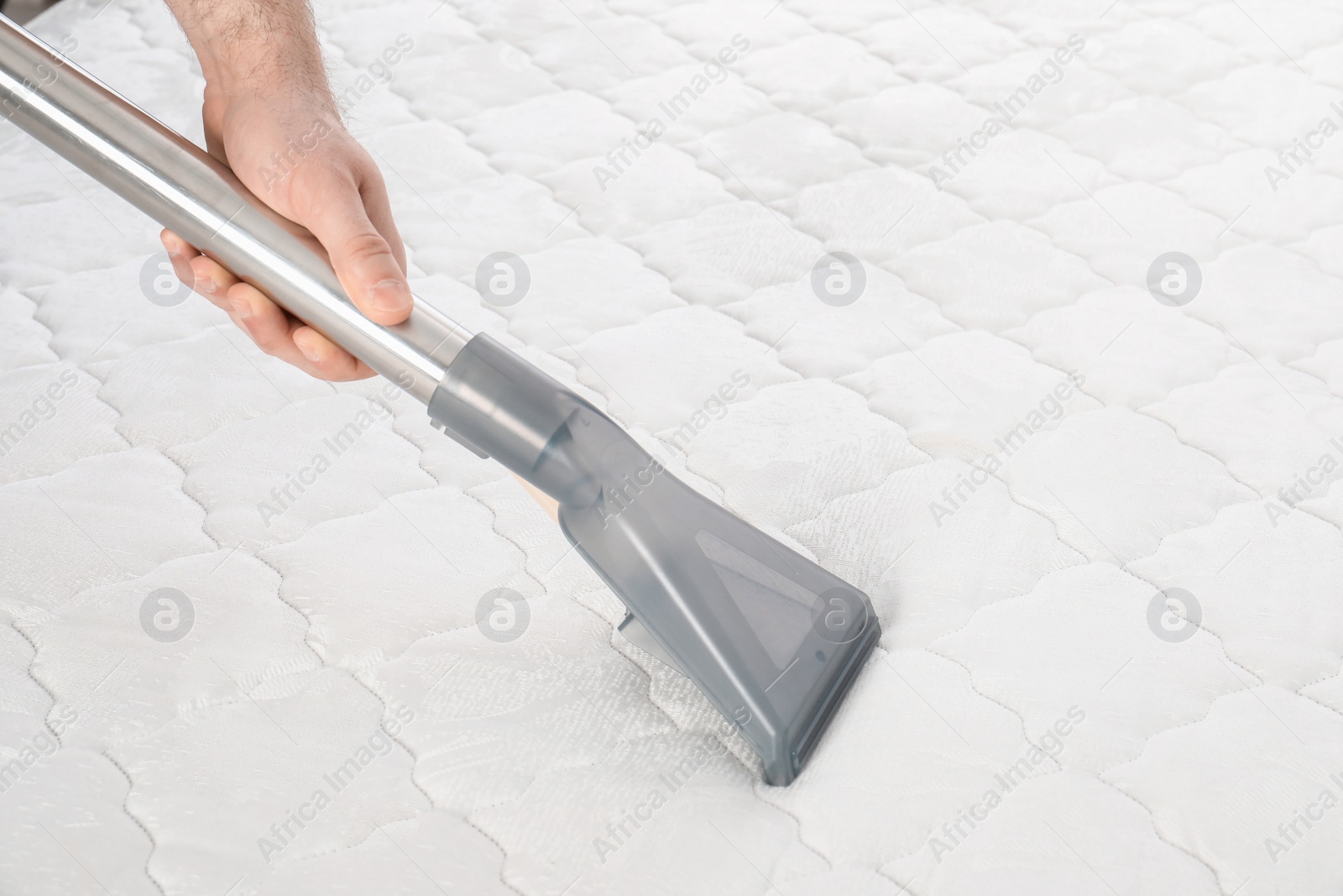 Photo of Man disinfecting mattress with vacuum cleaner, closeup. Space for text