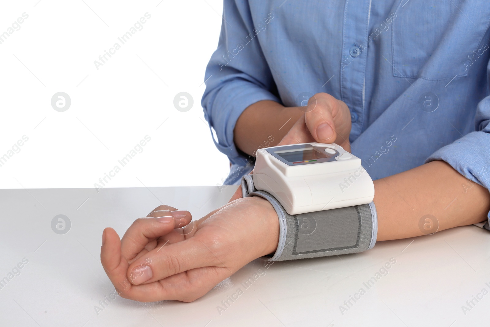 Photo of Woman checking blood pressure with sphygmomanometer at table against white background, closeup. Cardiology concept