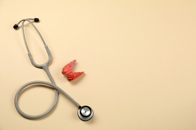 Photo of Endocrinology. Stethoscope and model of thyroid gland on beige background, top view. Space for text