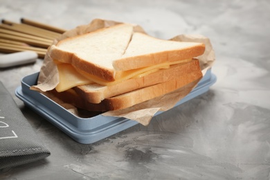 Photo of Lunch box with tasty sandwich and stationery on table