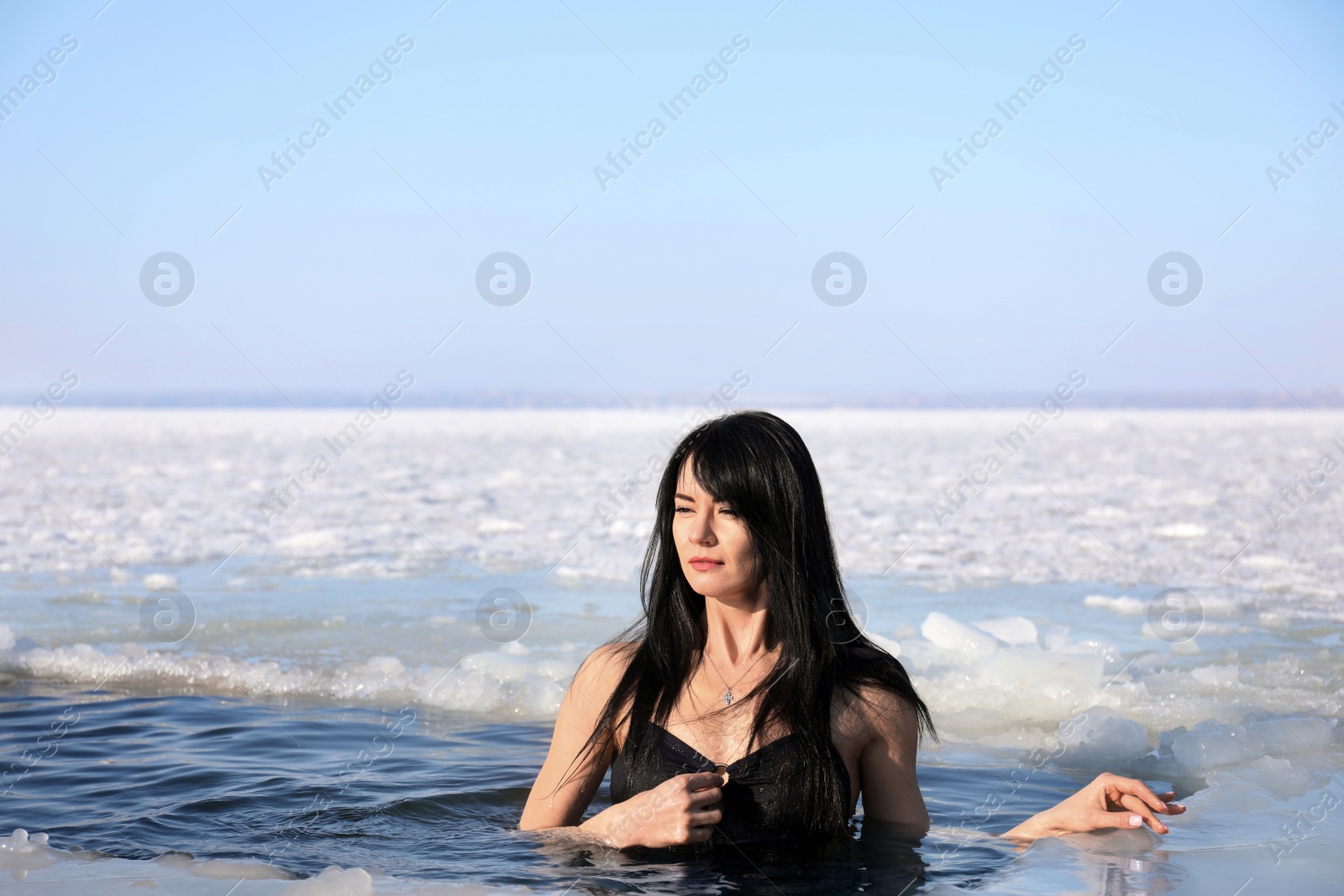 Photo of Woman immersing in icy water on winter day. Baptism ritual