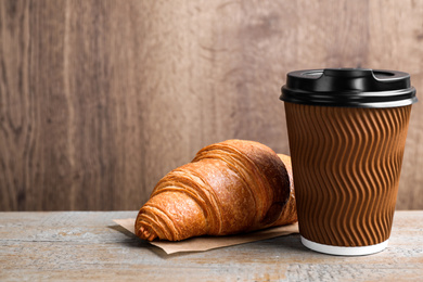Photo of Tasty fresh croissant and drink on wooden table