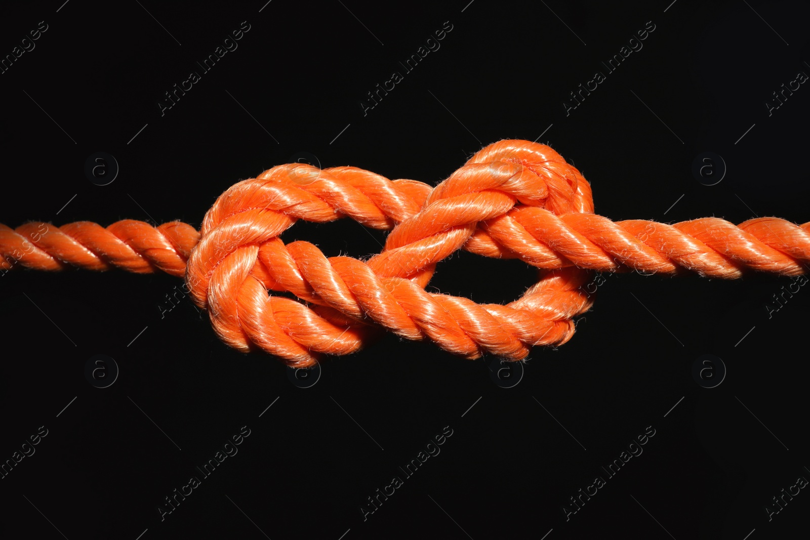 Photo of Orange rope with knot on black background