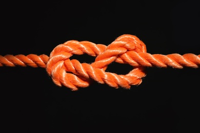 Photo of Orange rope with knot on black background