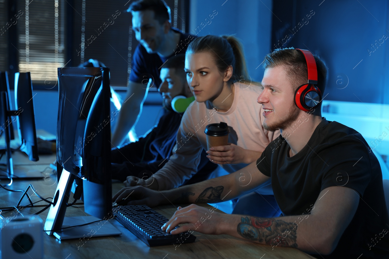 Photo of Group of people playing video games in internet cafe