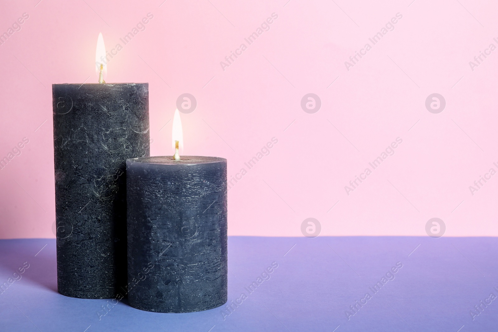 Photo of Decorative wax candles on table against color background