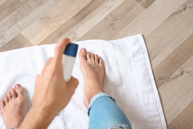 Photo of Young man using deodorant for feet at home, closeup