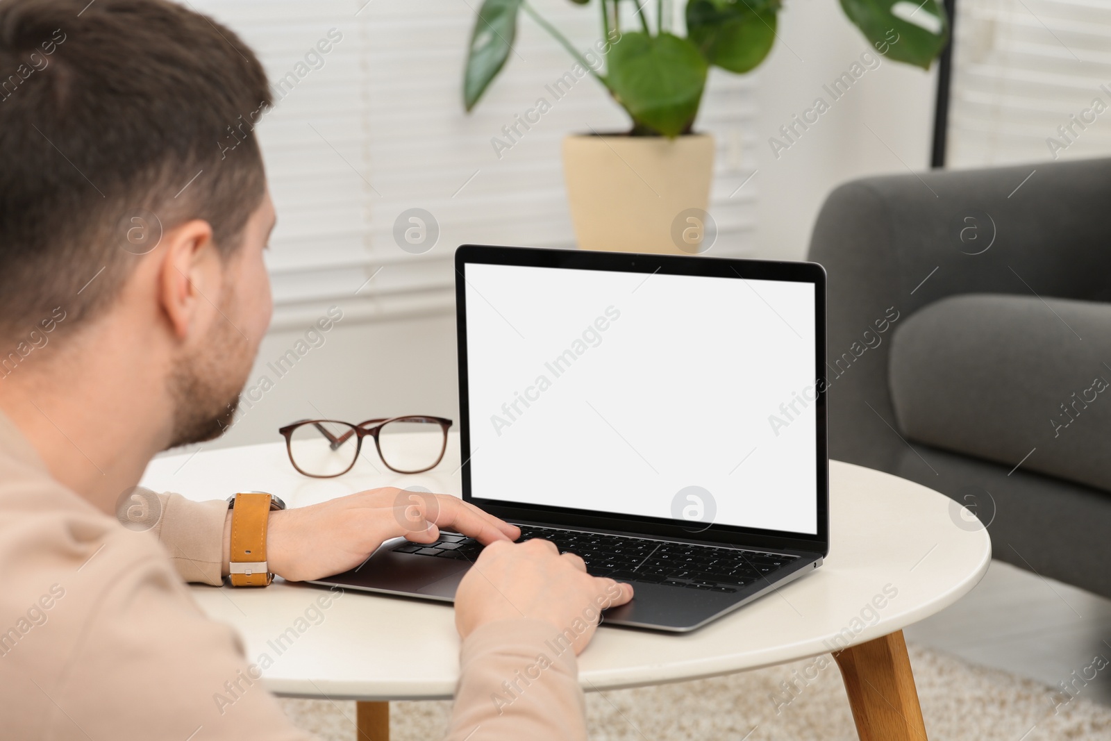 Photo of Man working with laptop at table in living room