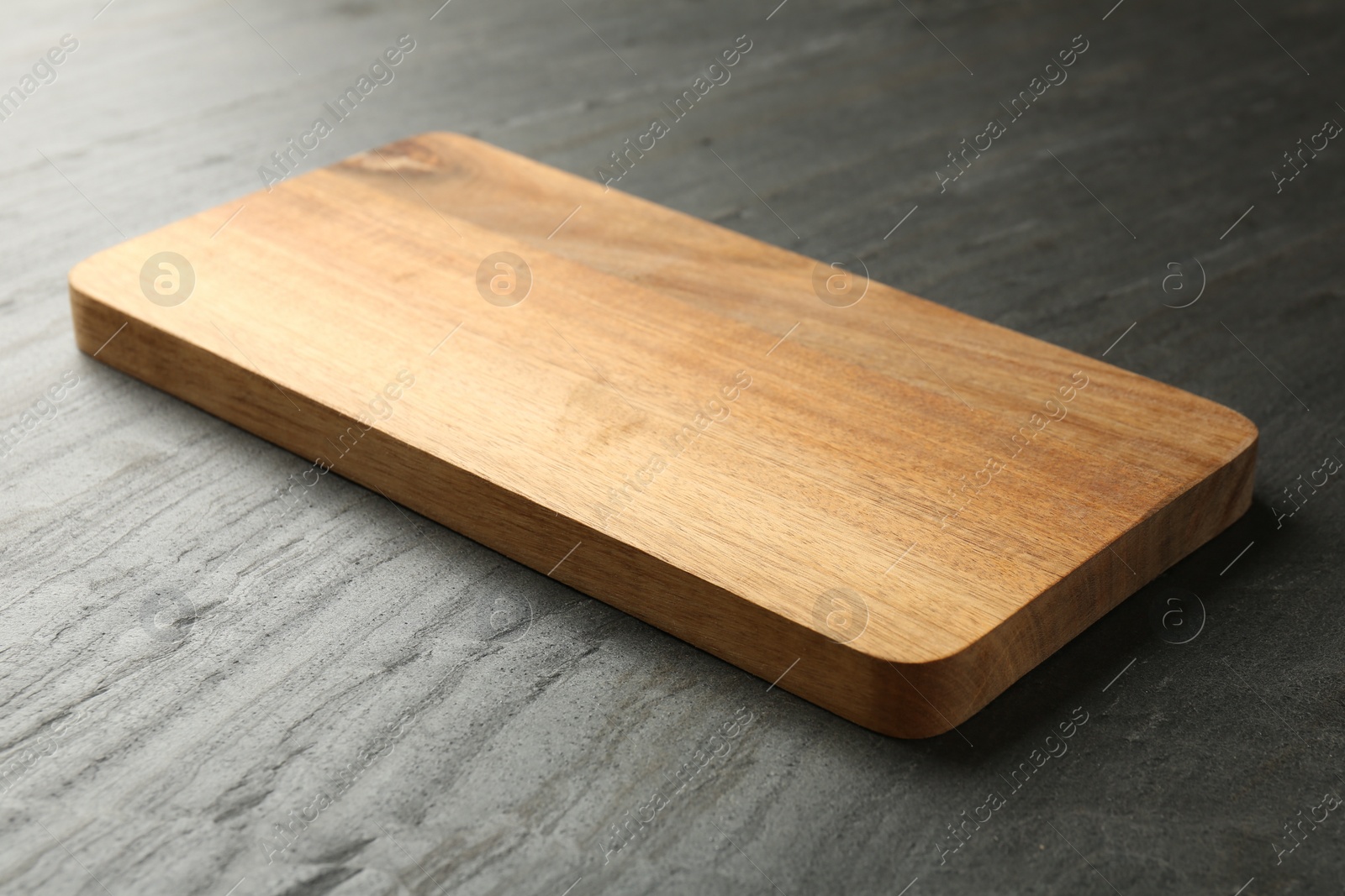 Photo of One wooden cutting board on dark grey table