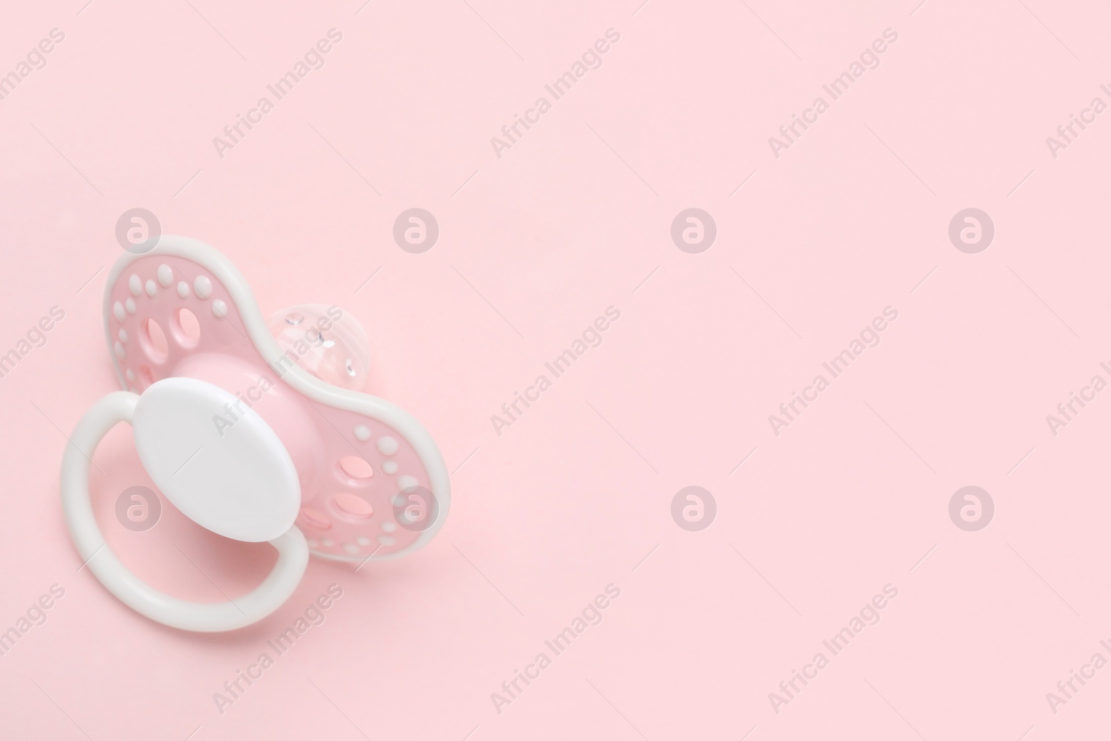 Photo of Baby pacifier on pink background. Space for text