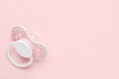 Photo of Baby pacifier on pink background. Space for text