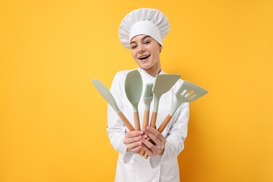 Professional chef with kitchen utensils on yellow background