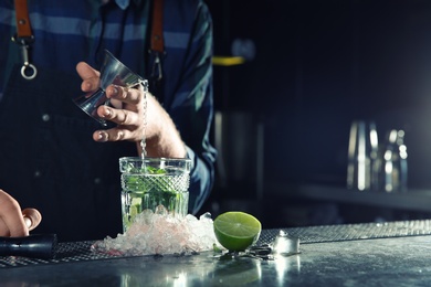 Photo of Barman making Mojito cocktail at counter in pub, closeup. Space for text