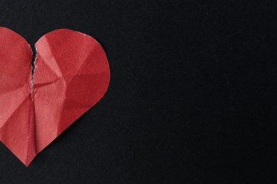 Photo of Crumpled torn paper heart on black background, top view with space for text. Breakup concept