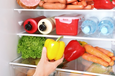 Photo of Woman taking bell pepper from refrigerator, closeup