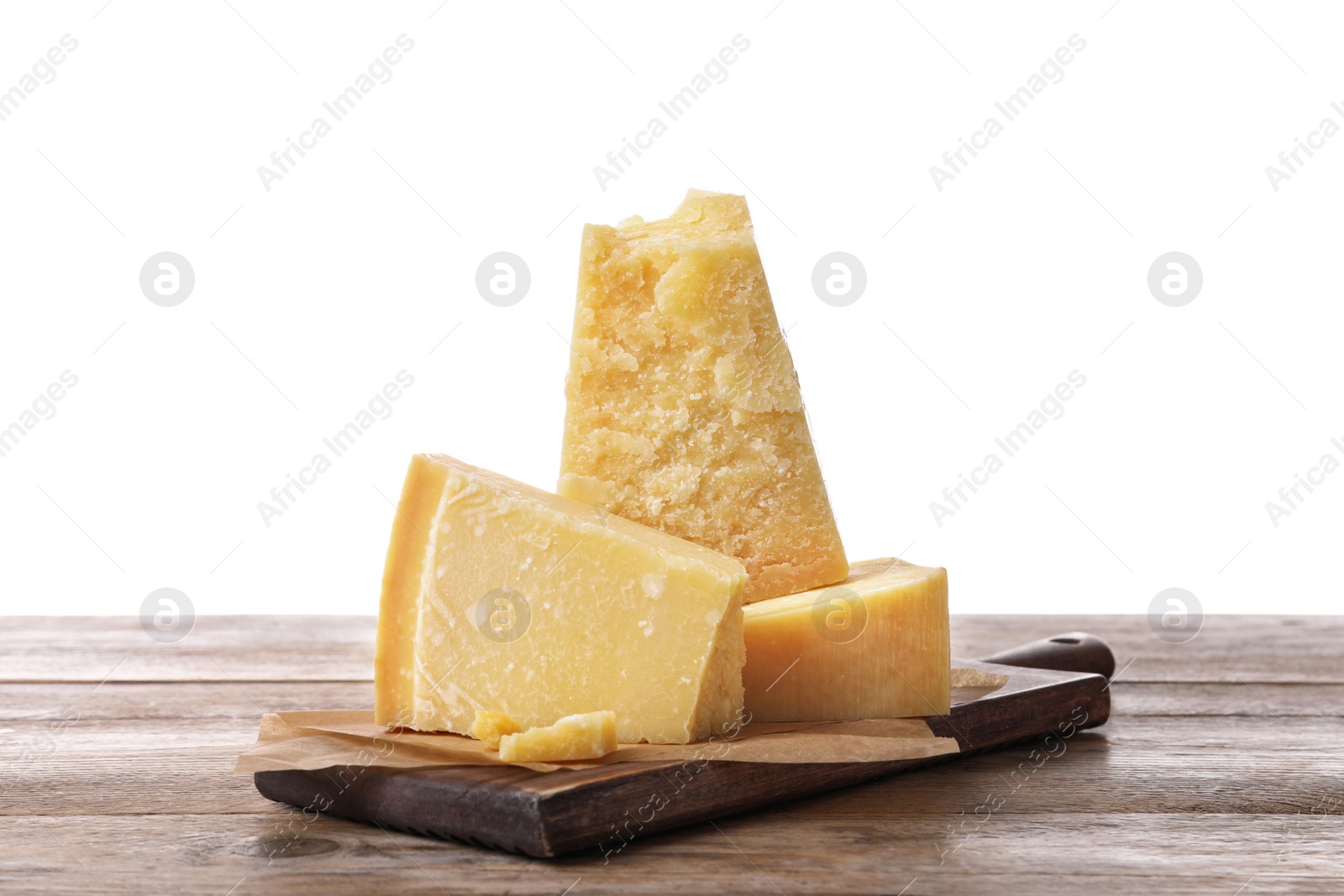 Photo of Pieces of delicious parmesan cheese on wooden table against white background