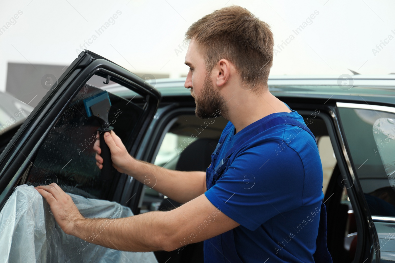 Photo of Worker washing tinted car window in workshop