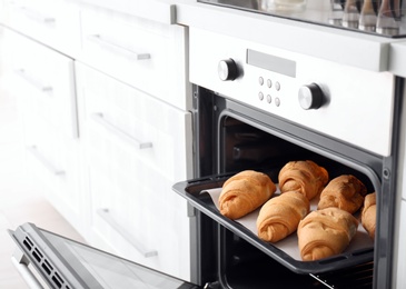 Baking tray with delicious croissants in oven