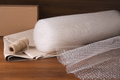 Twine, paper and roll of bubble wrap on wooden table