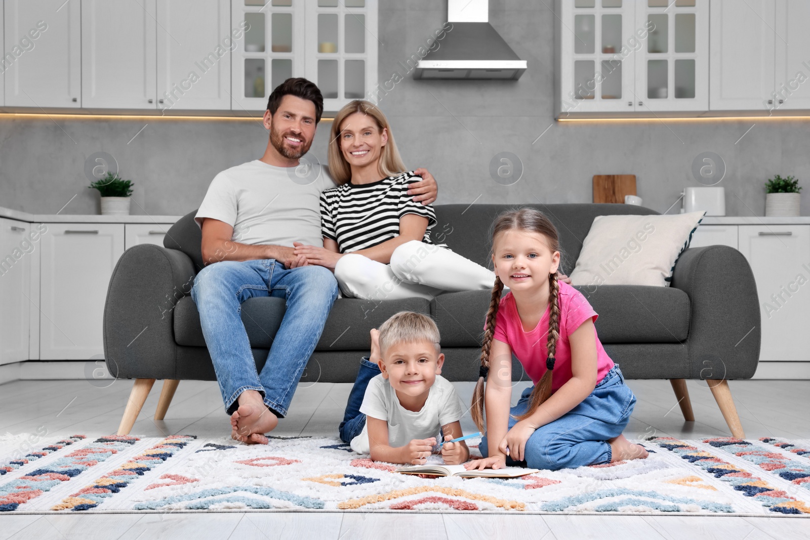 Photo of Happy couple spending time together while their children drawing on floor at home