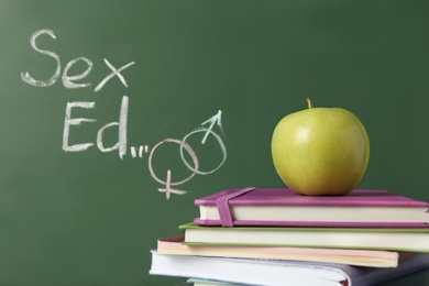 Photo of Books and apple near chalkboard with phrase "Sex ed"