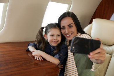 Photo of Mother with daughter taking selfie in airplane during flight