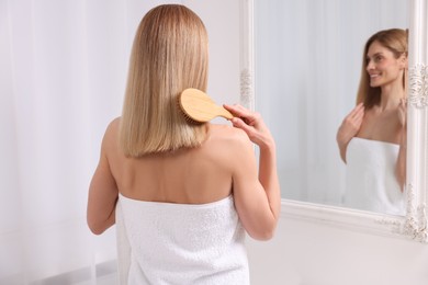 Photo of Woman after shower brushing her hair near mirror in room