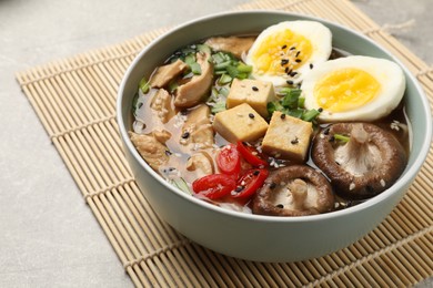 Photo of Bowl of delicious ramen on grey table, closeup. Noodle soup