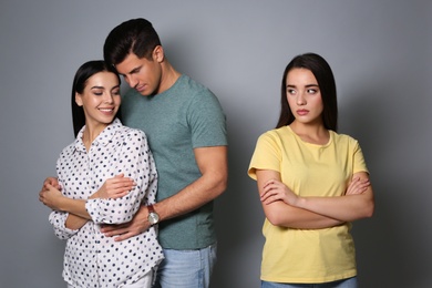 Photo of Unhappy woman feeling jealous while couple spending time together on grey background
