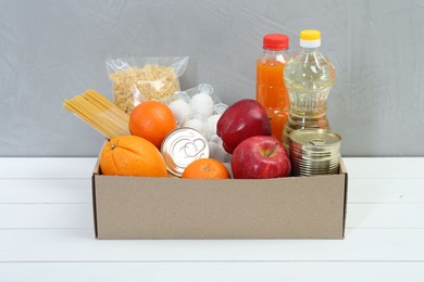 Humanitarian aid. Different food products for donation in box on white wooden table