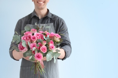 Photo of Male florist holding bouquet of beautiful flowers on light background