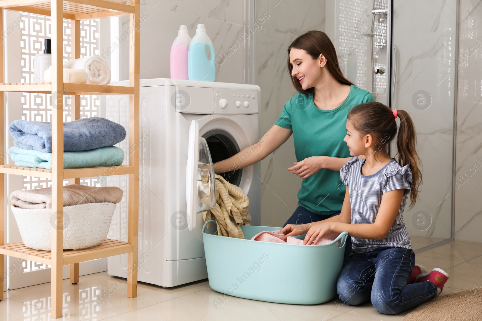 Photo of Mother and little daughter with clean laundry in bathroom