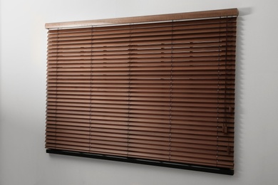 Photo of Modern window with closed stylish wooden blinds indoors. Space for text