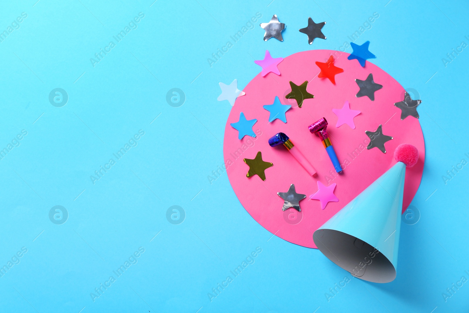 Photo of Party hat, confetti and blowers on light blue background, flat lay. Space for text