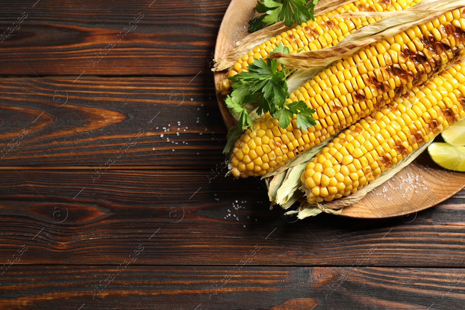 Photo of Delicious grilled corn cobs on wooden table, top view. Space for text