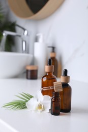 Photo of Essential oils and orchid flower on white table in bathroom